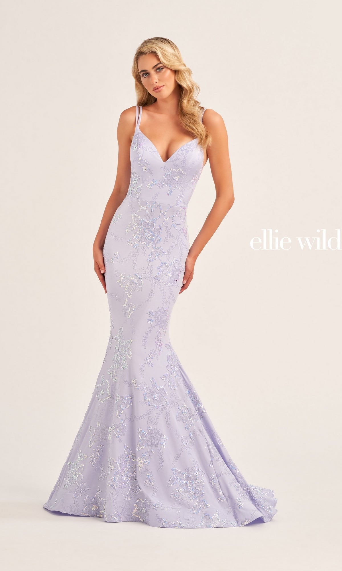 A woman wears the Ellie Wilde Long Mermaid Formal Dress EW35083, a fitted lavender mermaid gown with thin straps and subtle sequin details, standing against a plain light background.